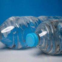 Close-up of clear plastic water bottles with blue caps on a blue background.